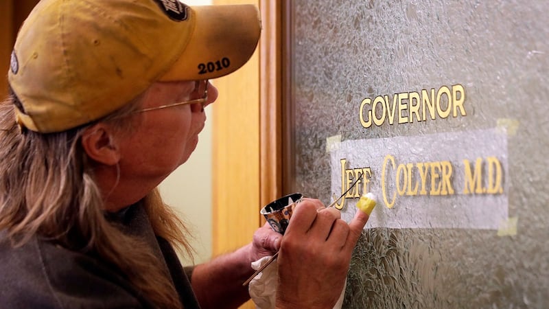 Sign painter Bob Sell paints Jeff Colyer's name on the Governor's office door. Colyer is to be...