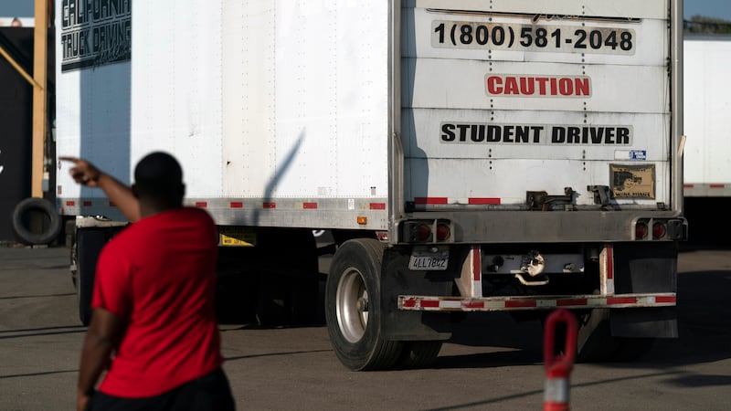 FILE - A student driver helps his classmate steer the wheel into the right direction as they...