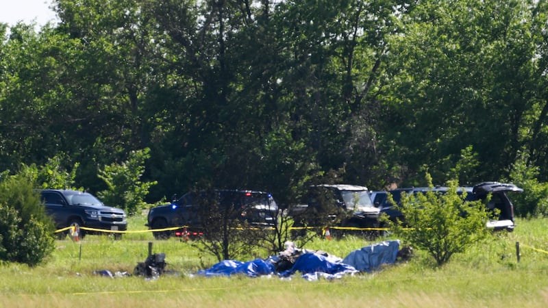 Part of the wreckage of a plane crash is covered with a blue tarp at Butler Memorial Airport...
